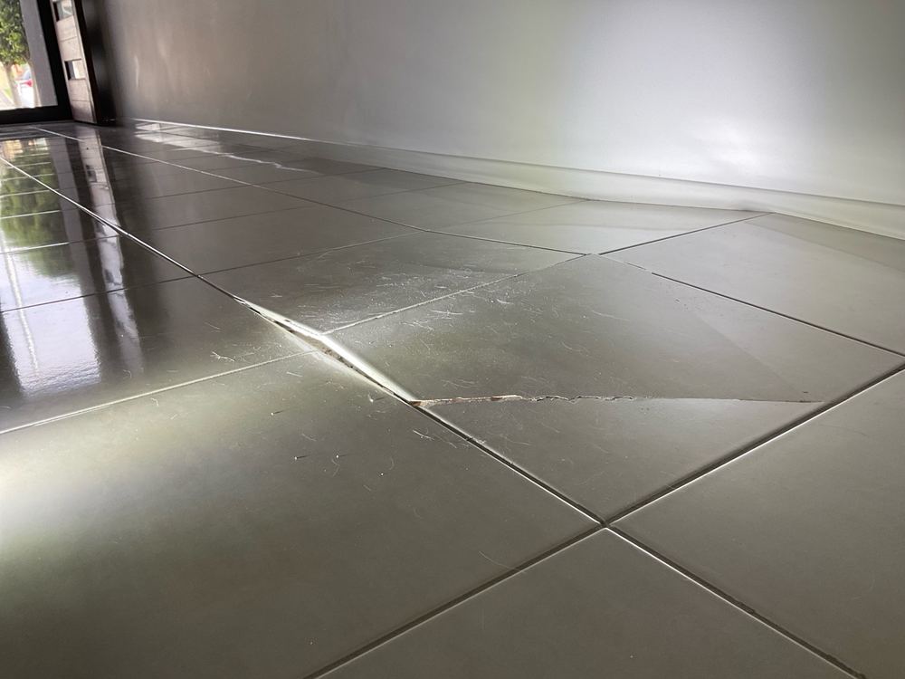 Floor tiles lifting into a peak and cracking along the joint, found during a defect investigation inspection in Werribee